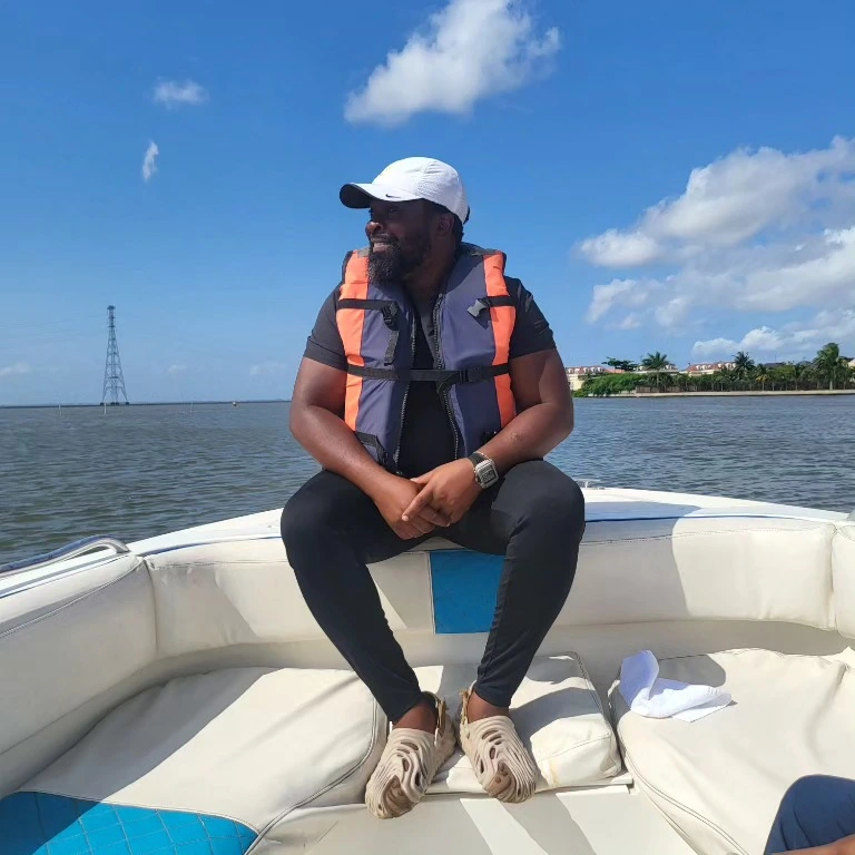 Olukayode sitting at the bow of a boat on the water